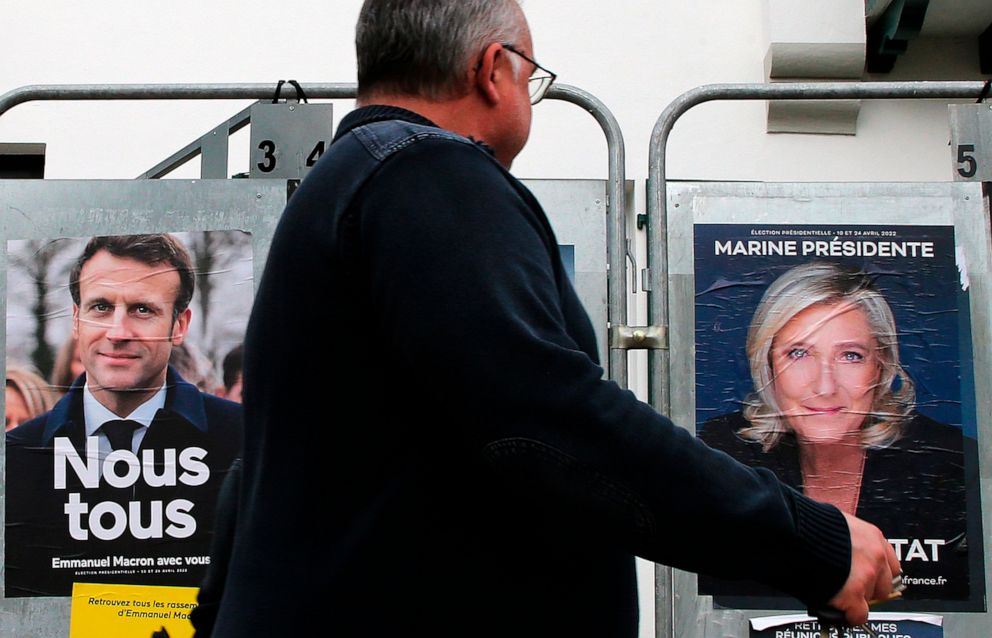 PHOTO: A man walks past presidential campaign posters of French President Emmanuel Macron and French far-right presidential candidate Marine Le Pen in Anglet, southwestern France, April 8, 2022.