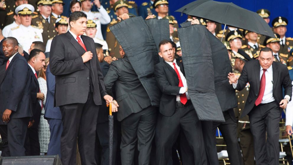 In this photo released by China's Xinhua News Agency, security personnel surround Venezuela's President Nicolas Maduro during an incident as he was giving a speech in Caracas, Venezuela, Saturday, Aug. 4, 2018.