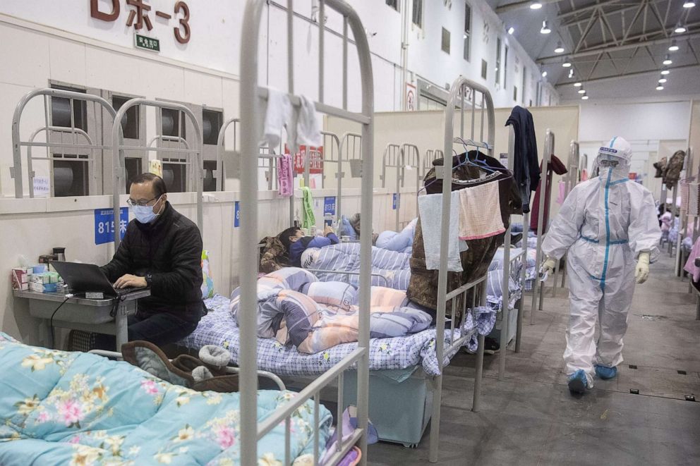 PHOTO: This photo taken on Feb. 17, 2020, shows a man (L) who has displayed mild symptoms of the novel coronavirus using a laptop at an exhibition center converted into a hospital in Wuhan in China's central Hubei province.