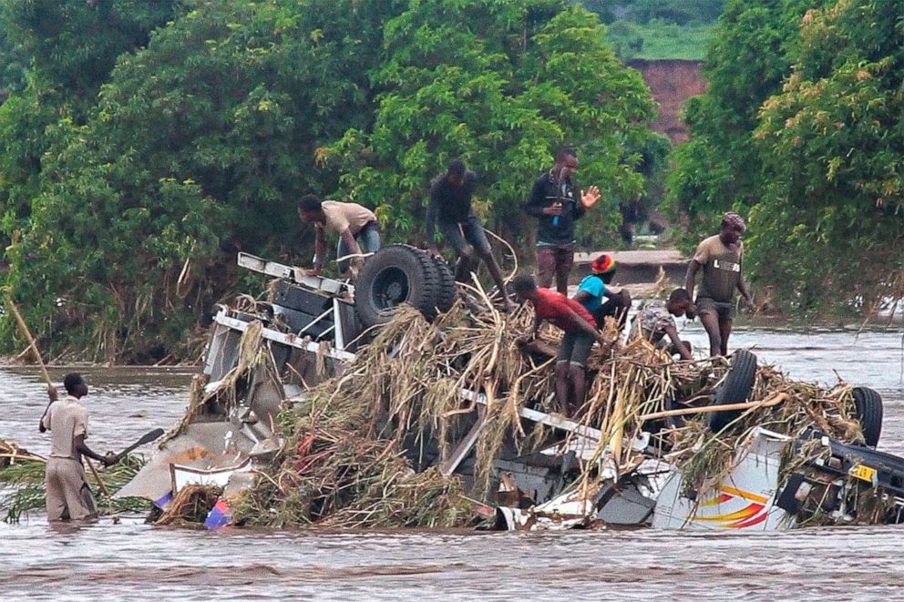 PHOTO: People stand on an overturned vehicle swept by flooding waters in Chikwawa, Malawi, Jan. 25, 2022.