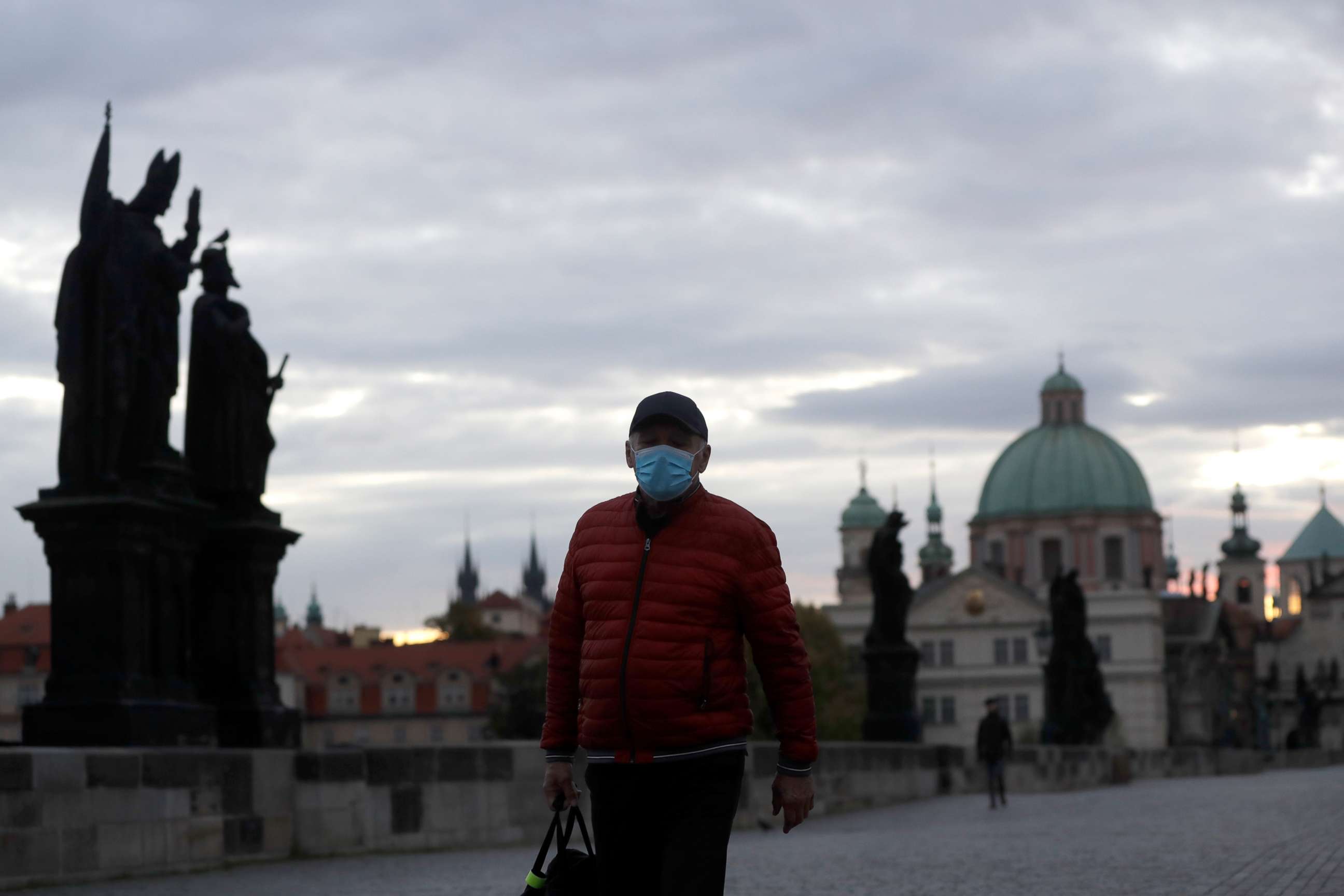 PHOTO: A man wearing a face mask to protect against the novel coronavirus crosses the medieval Charles Bridge in Prague, Czech Republic, on Oct. 8, 2020.