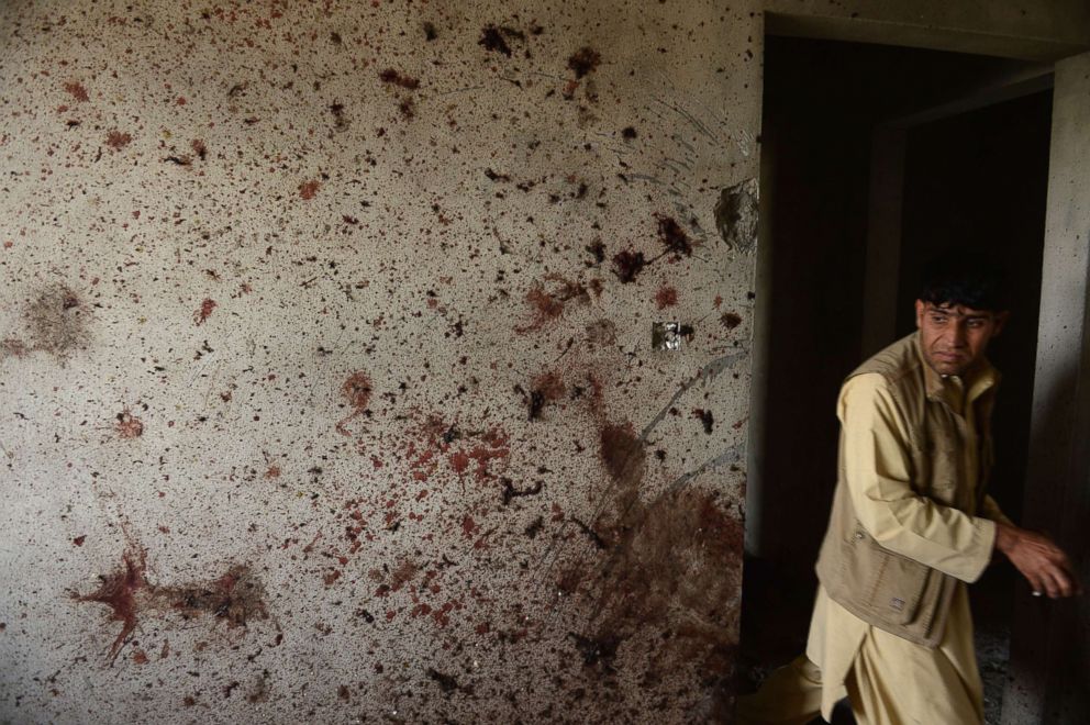 PHOTO: An Afghan man walks past a blood-spattered wall following a Taliban led suicide attack at Kabul's airport, July 17, 2014. 