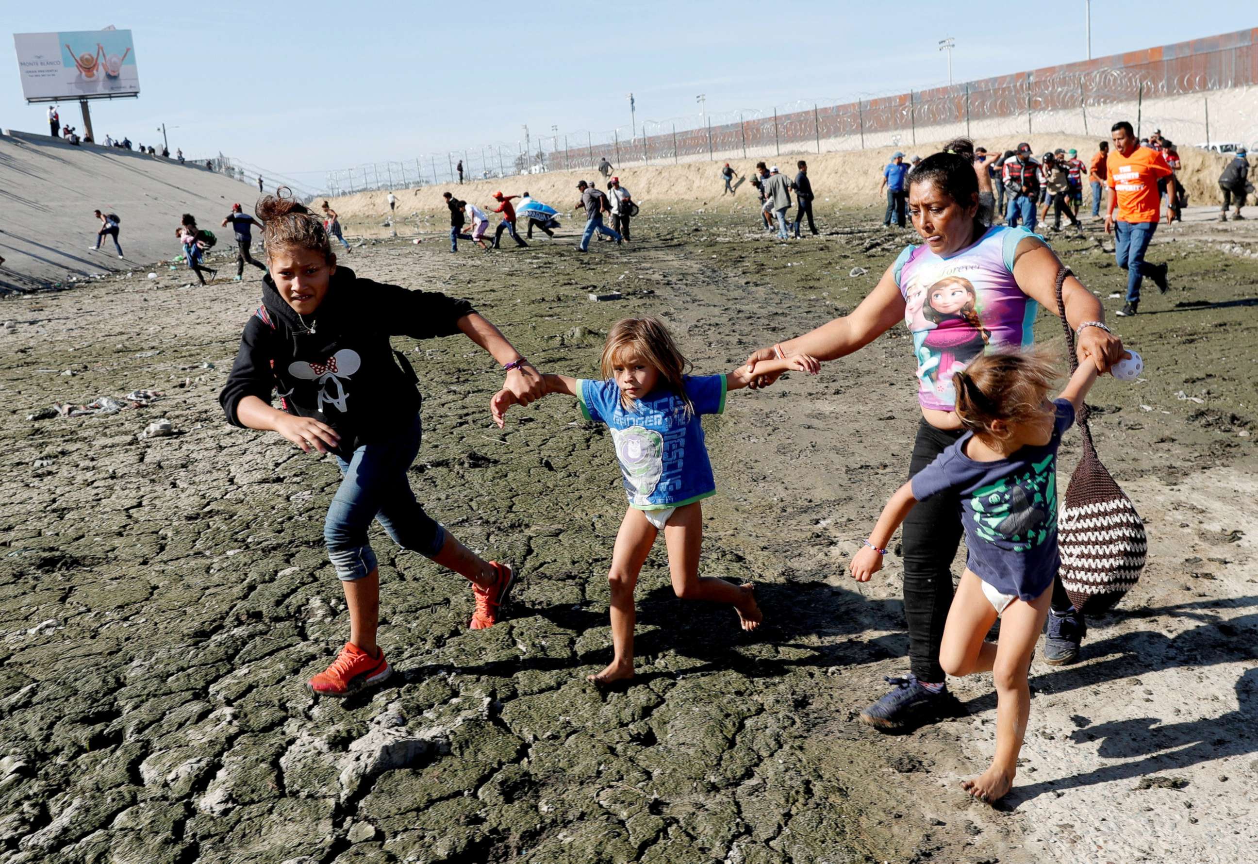 PHOTO: Maria Meza runs away from tear gas with her daughters Jamie Mejia Meza, aged 12 and her five-year-old twin daughters Saira Mejia Meza and Cheili Mejia Meza in front of the border wall between the U.S and Mexico, in Tijuana, Mexico Nov. 25, 2018.