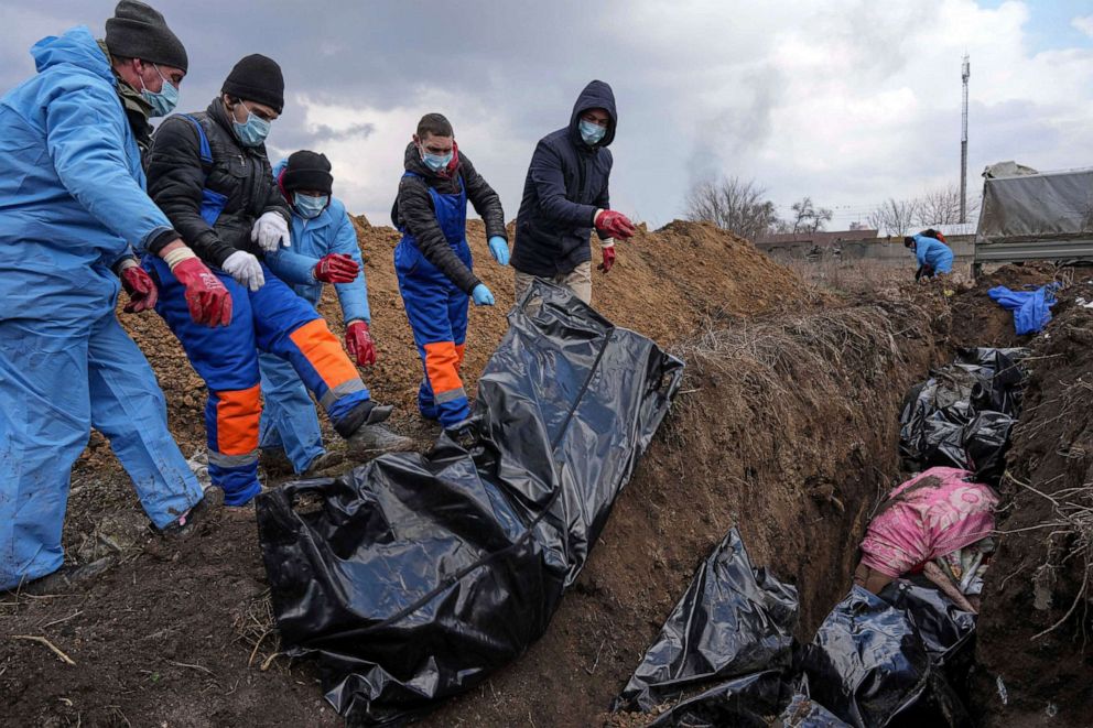 FOTOĞRAF: Rus kuvvetlerinin yoğun bombardımanı nedeniyle insanlar ölüleri gömemediği için 9 Mart 2022, Mariupol, Ukrayna'nın eteklerinde cesetler toplu bir mezara yerleştirildi.