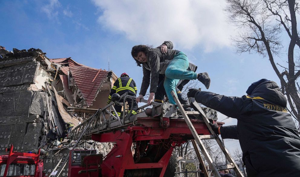 FOTOĞRAF: İtfaiyeciler, 10 Mart 2022'de Ukrayna'nın Mariupol kentinde bombardıman sonucu hasar gören bir apartmandan bir kadının tahliyesine yardım ediyor.