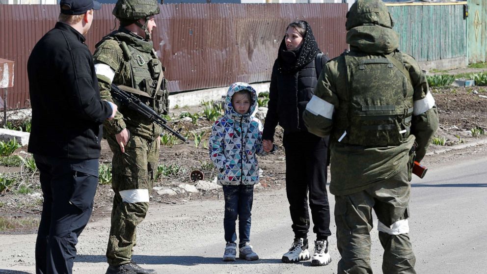 PHOTO: A woman with a child talks to service members of pro-Russian troops as evacuees board buses to leave the city during Ukraine-Russia conflict in the southern port of Mariupol, Ukraine, April 20, 2022.