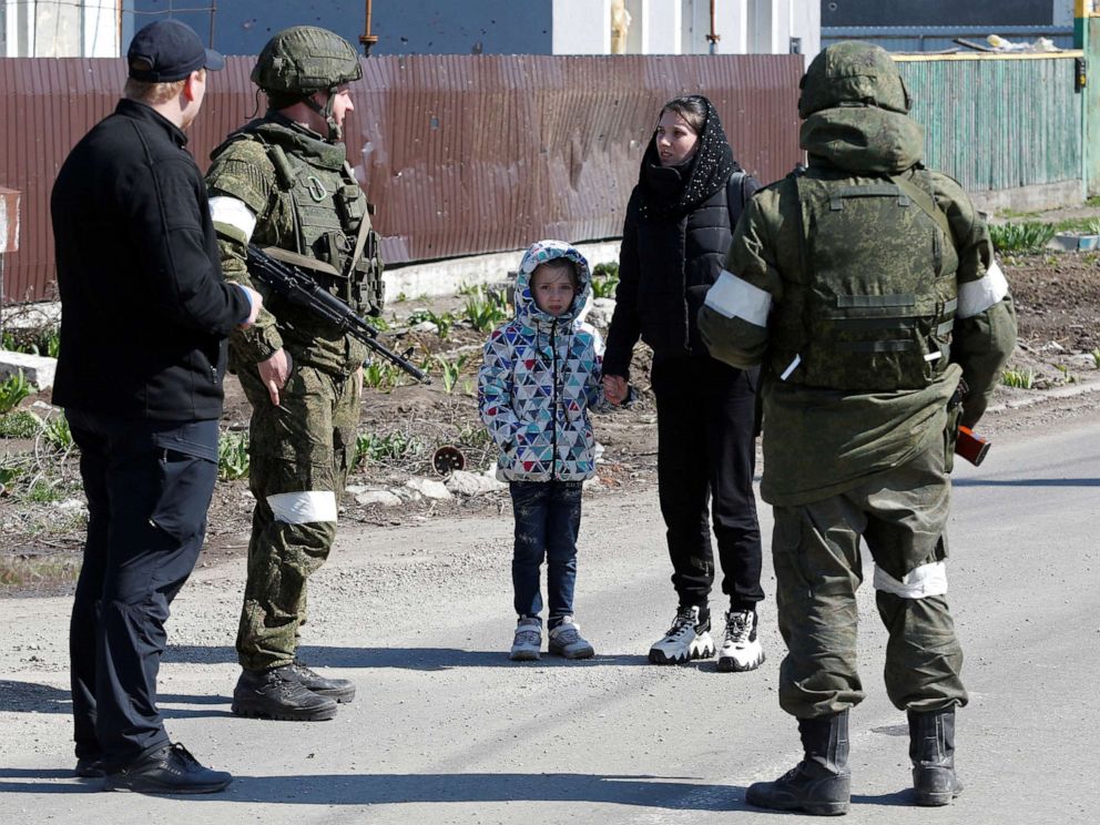 PHOTO: A woman with a child talks to service members of pro-Russian troops as evacuees board buses to leave the city during Ukraine-Russia conflict in the southern port of Mariupol, Ukraine, April 20, 2022.