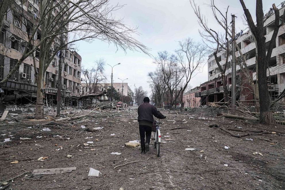 FOTOĞRAF: 10 Mart 2022'de Ukrayna'nın Mariupol kentinde bombalama sonucu hasar gören bir sokakta bisikletle yürüyen bir adam.
