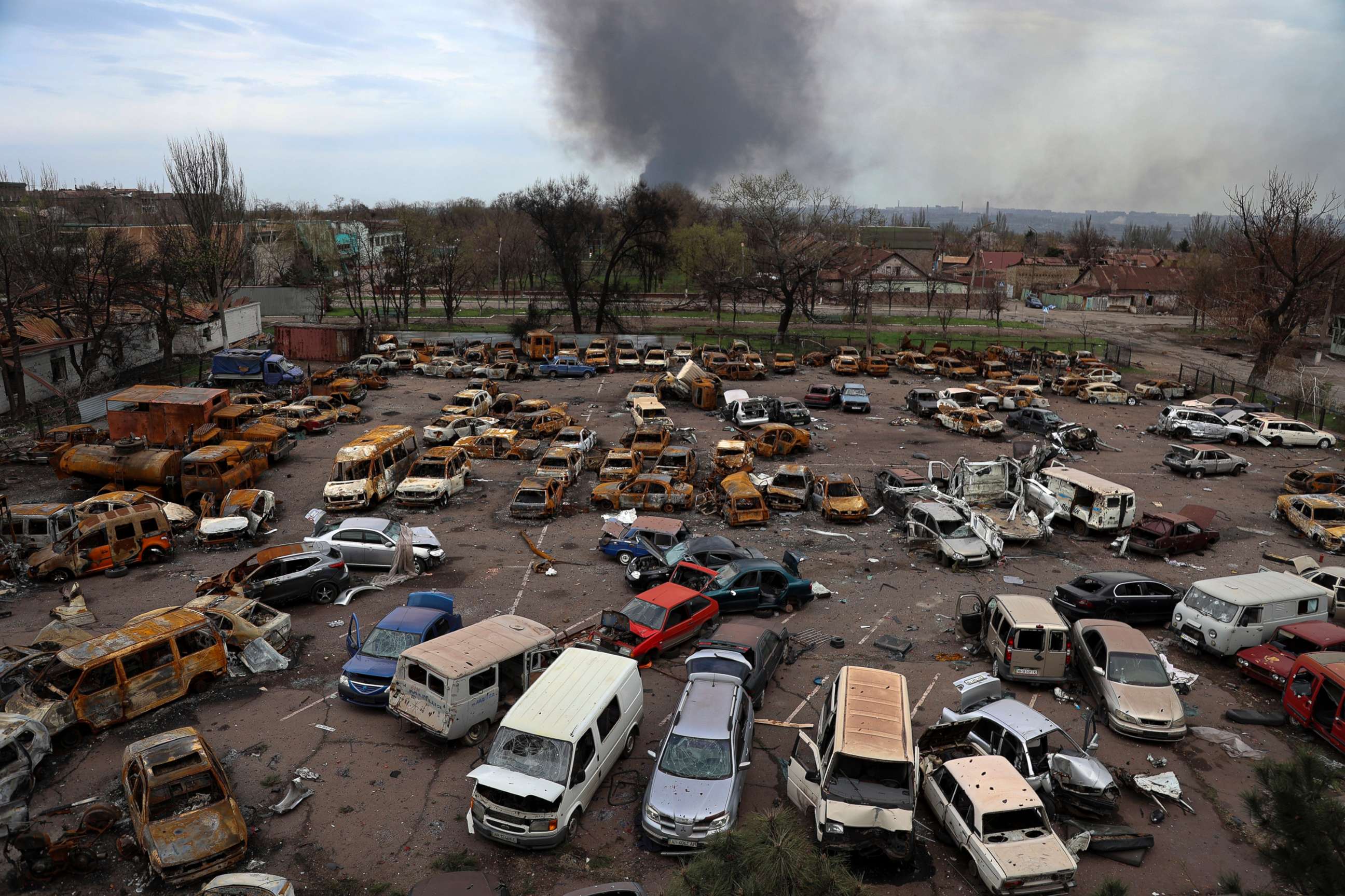 PHOTO: Damaged and burned vehicles are seen at a destroyed part of the Illich Iron & Steel Works Metallurgical Plant, as smoke rises from the Metallurgical Combine Azovstal during heavy fighting, in Mariupol, Ukraine, April 18, 2022.