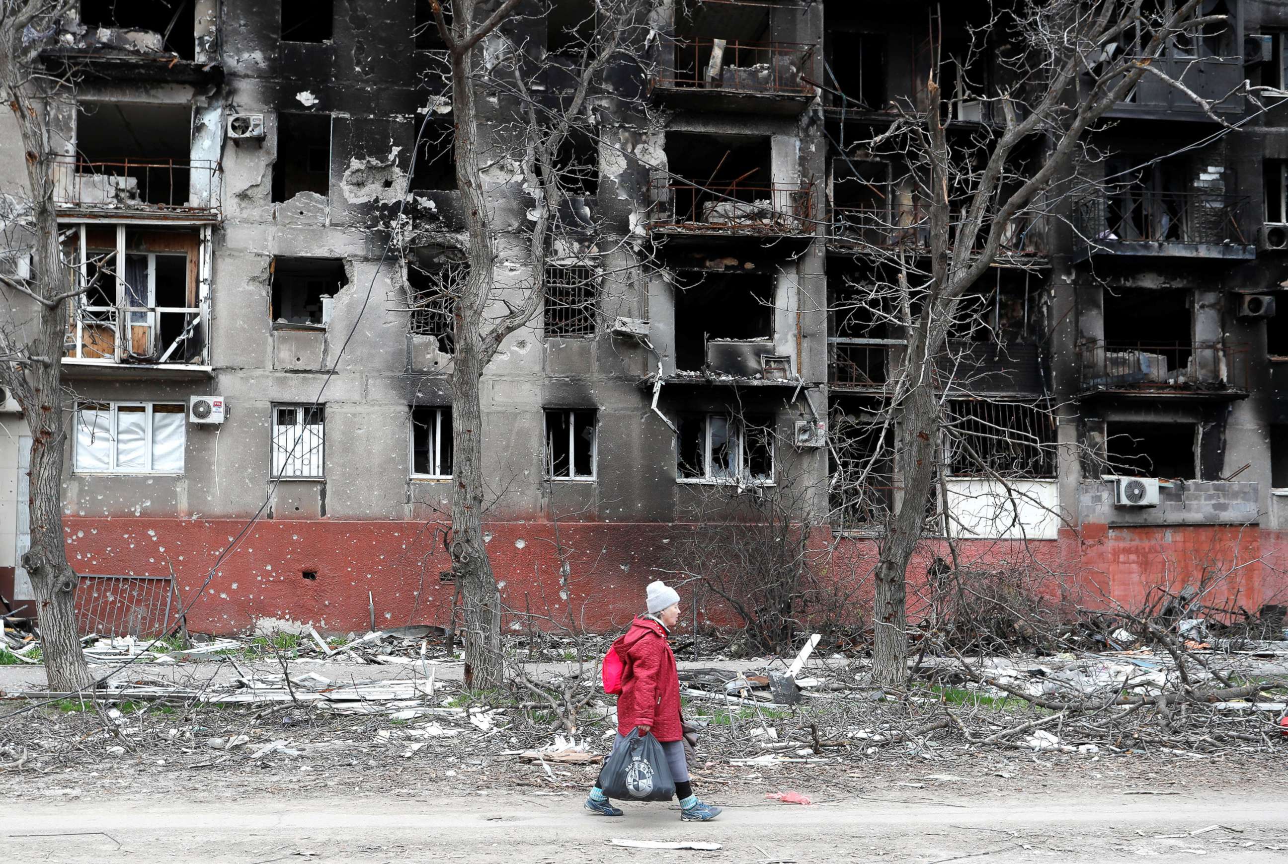 PHOTO: An elderly woman walks past a residential building heavily damaged during Ukraine-Russia conflict in the southern port city of Mariupol, Ukraine April 21, 2022.