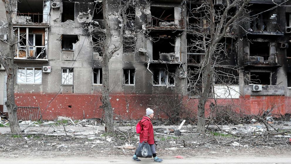 PHOTO: An elderly woman walks past a residential building heavily damaged during Ukraine-Russia conflict in the southern port city of Mariupol, Ukraine April 21, 2022.