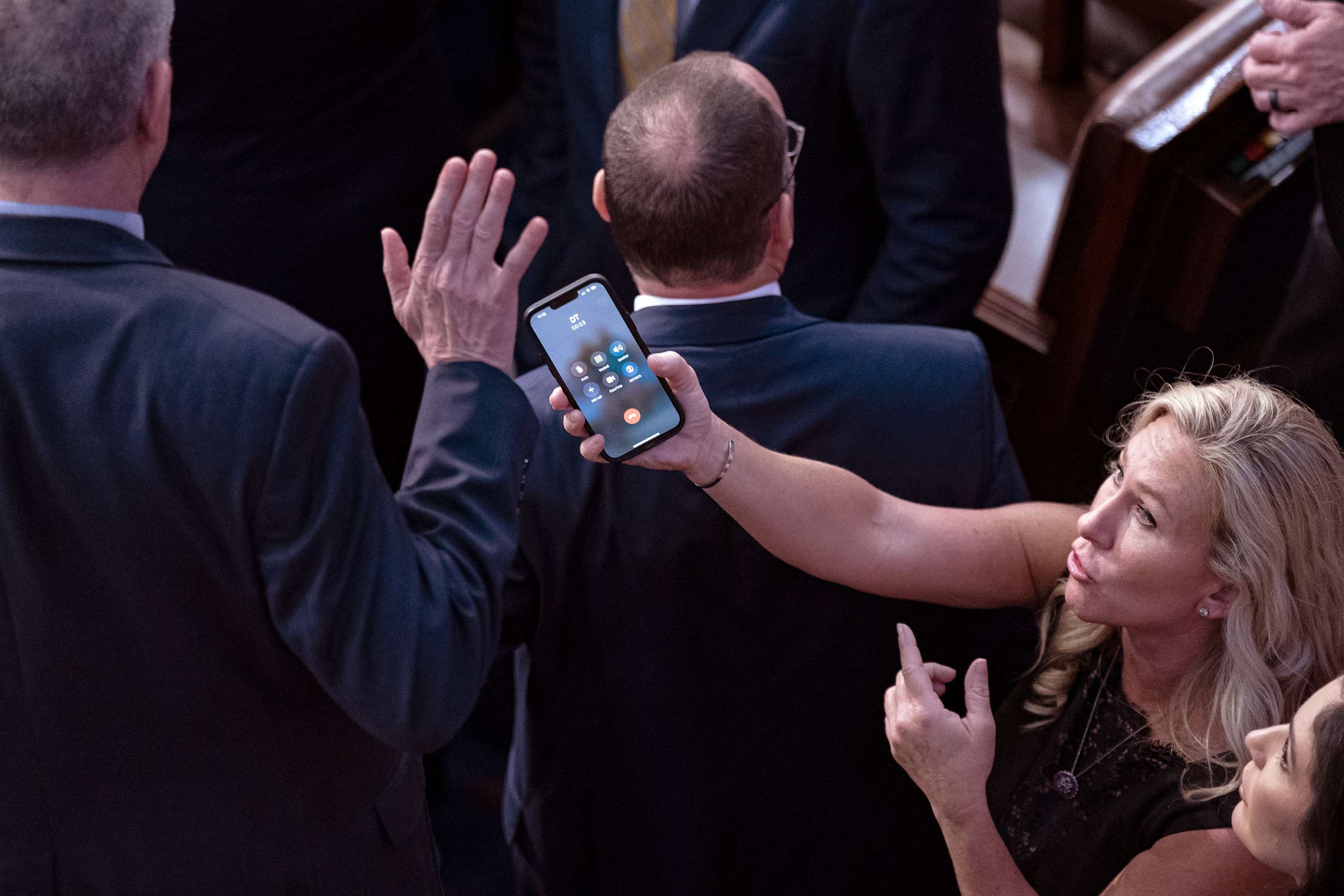 PHOTO: Rep.-elect Marjorie Taylor Greene holds her smart phone with former President Donald Trump on the line, as Rep.-elect Matt Rosendale waves it off during a meeting of the 118th Congress at the US Capitol in Washington, D.C. on Jan. 6, 2023.