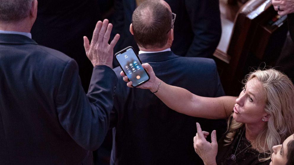 PHOTO: Rep.-elect Marjorie Taylor Greene holds her smart phone with former President Donald Trump on the line, as Rep.-elect Matt Rosendale waves it off during a meeting of the 118th Congress at the US Capitol in Washington, D.C. on Jan. 6, 2023.