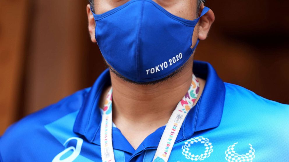 PHOTO: A staff member of the Tokyo 2020 Olympic and Paralympic Games wears a face mask stands to protect against COVID-19 while standing at the entrance to the Village Plaza near the Olympic and Paralympic Village in Tokyo, Japan, on June 20, 2021.