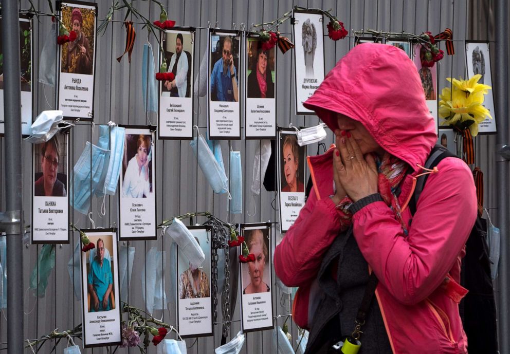PHOTO: A woman reacts as she walks past portraits of medical workers who died from the novel coronavirus, displayed at an unofficial memorial in front of the local health department in Saint Petersburg, Russia, on May 20, 2020.