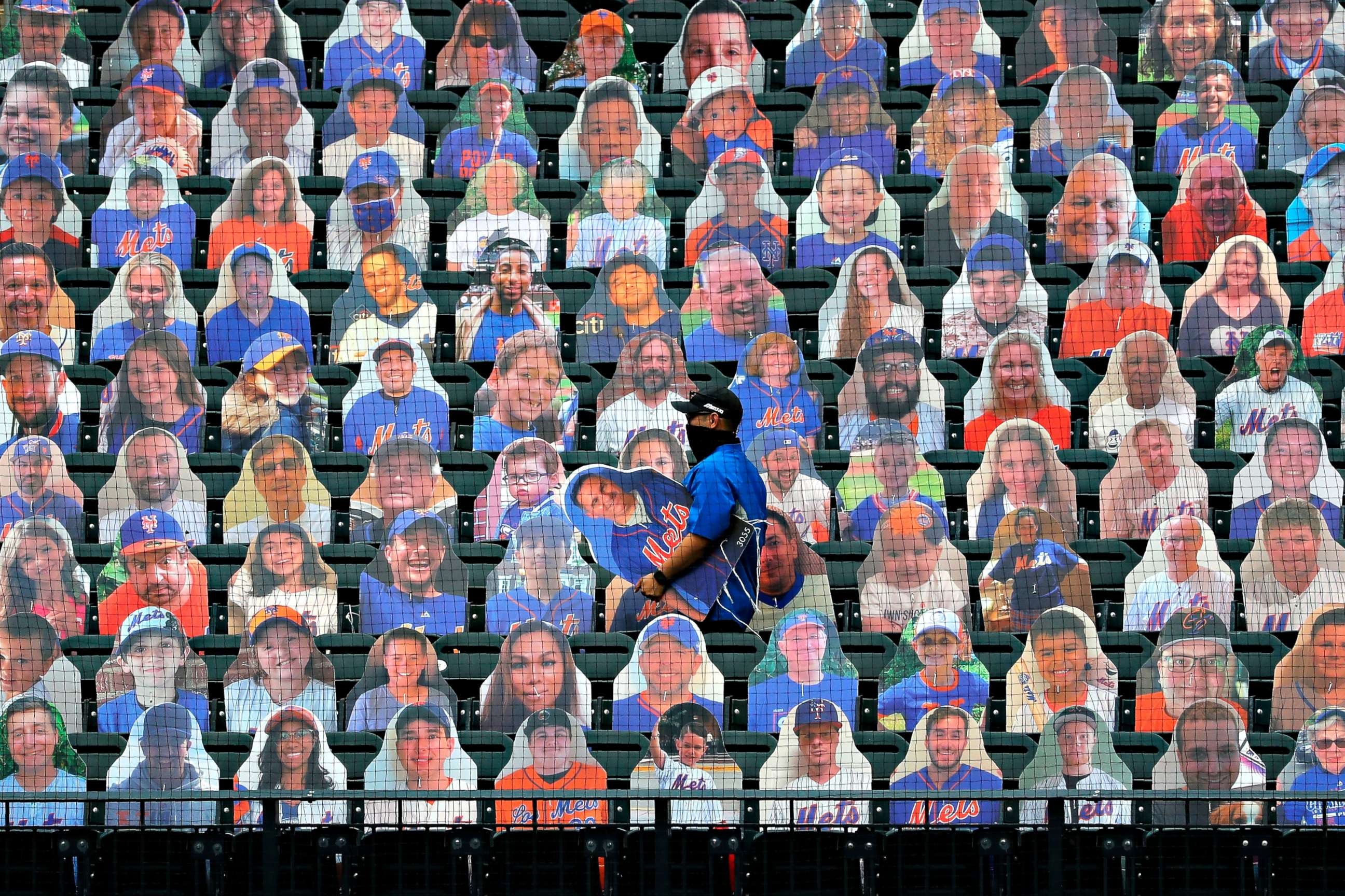 PHOTO: New York Mets employees place cutouts of fans in the seats before the opening day baseball game between the Mets and the Atlanta Braves at Citi Field on July 24, 2020, in New York City.