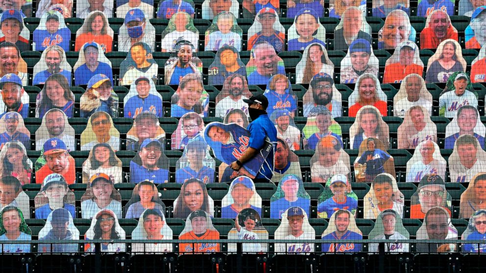 PHOTO: New York Mets employees place cutouts of fans in the seats before the opening day baseball game between the Mets and the Atlanta Braves at Citi Field on July 24, 2020, in New York City.