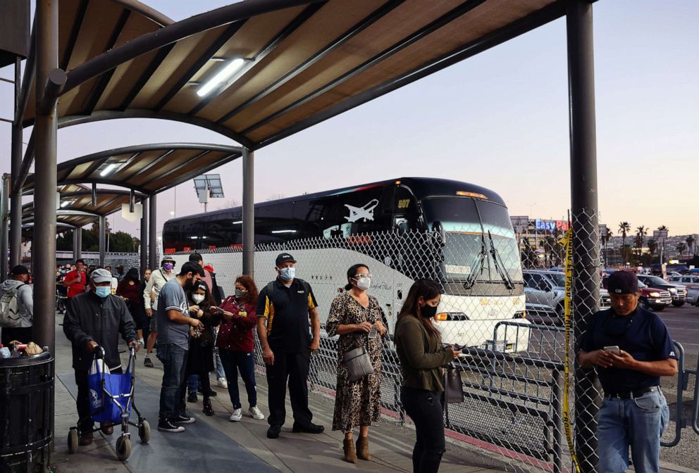 PHOTO: People wait in line on their way to cross the southern border into the United States near the San Ysidro Port of Entry on March 22, 2022. in Tijuana, Mexico.