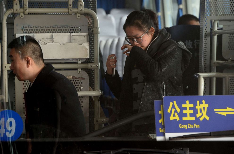 PHOTO: A crying woman is escorted to a bus for relatives of passengers of a missing Malaysia Airlines flight, MH-370, at Beijing International Airport in Beijing on March 8, 2014.