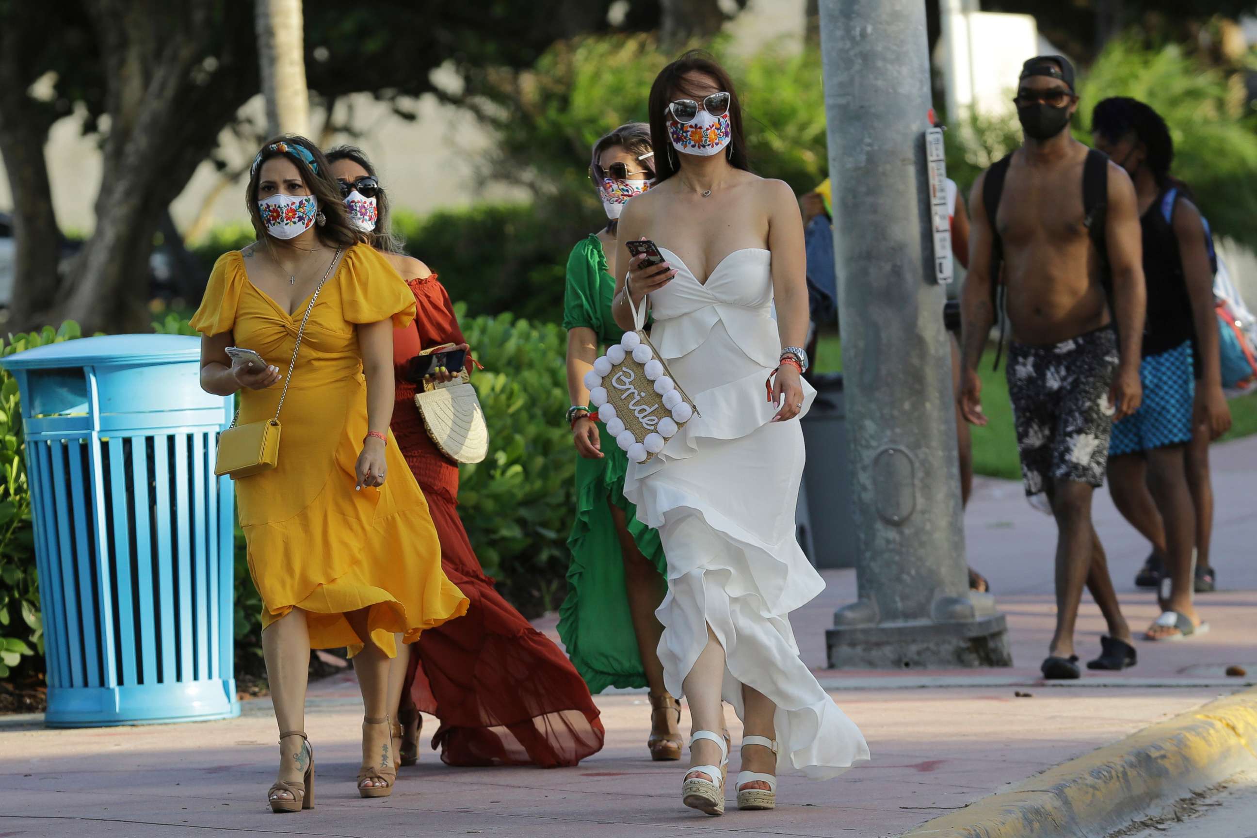 PHOTO: People wearing protective face masks walk along Ocean Drive during the coronavirus pandemic, July 24, 2020, in Miami Beach, Fla.