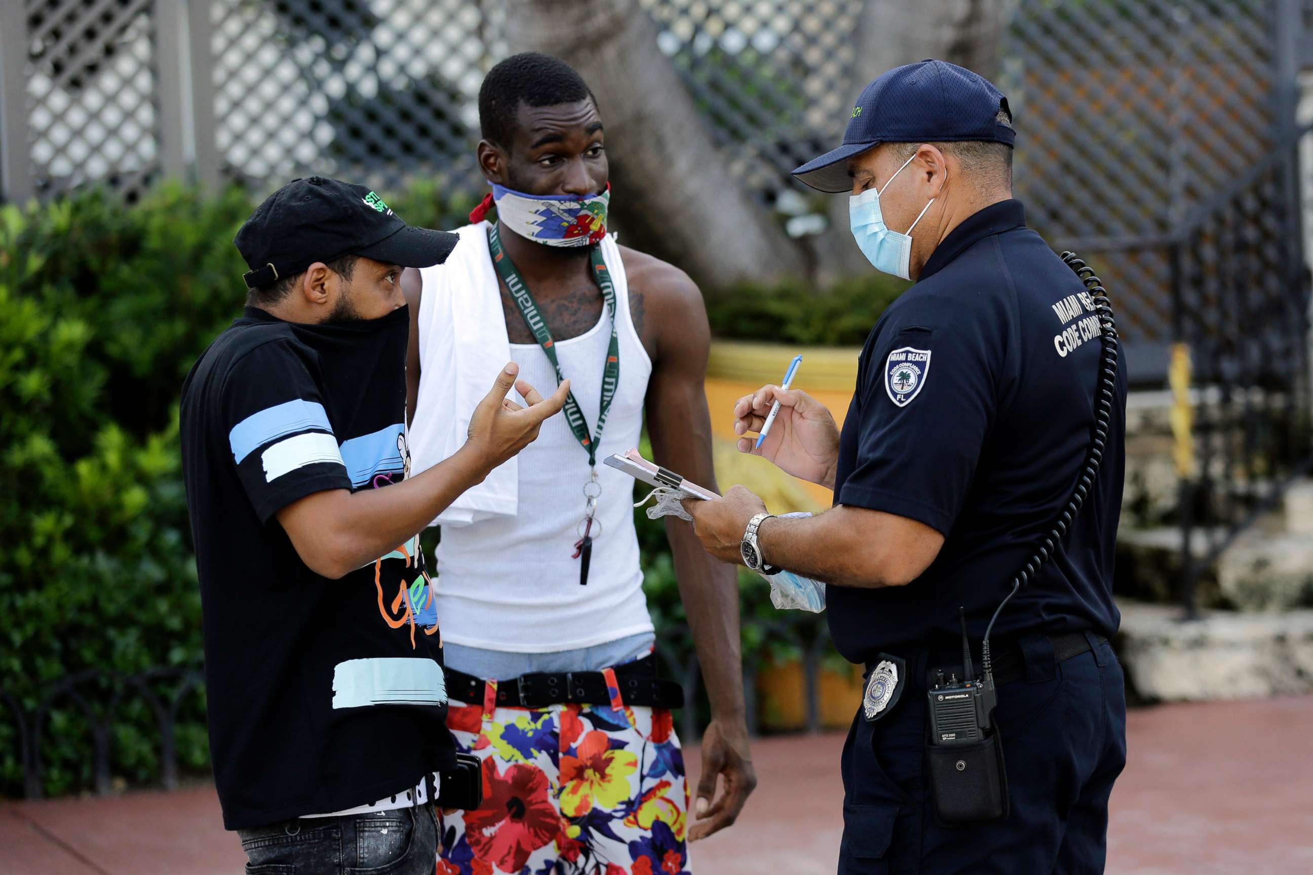 PHOTO: A man covers his nose with his shirt, left, as Luis Negron, a Miami Beach code compliance officer, right, talks to him about wearing a protective face mask amid the coronavirus pandemic on Ocean Drive in Miami Beach, Fla., July 24, 2020.