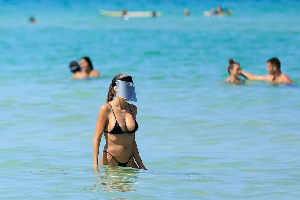 PHOTO: A woman wears a face shield as she wades in the ocean off South Beach in Miami Beach, Fla., on June 10, 2020.