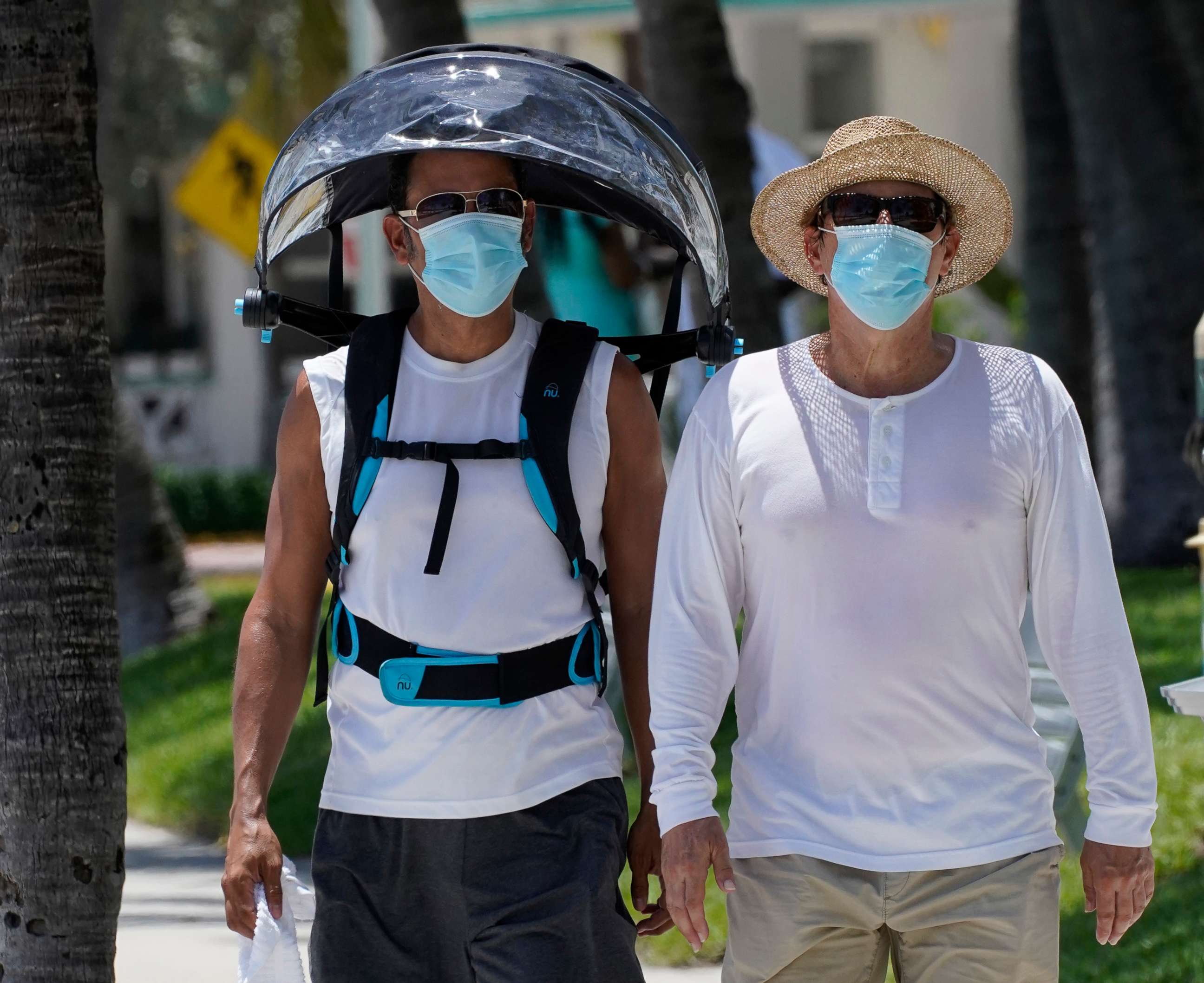 PHOTO: A pair of beach goers wear masks to prevent the spread of COVID-19, Aug. 11, 2020, in Miami Beach, Fla.