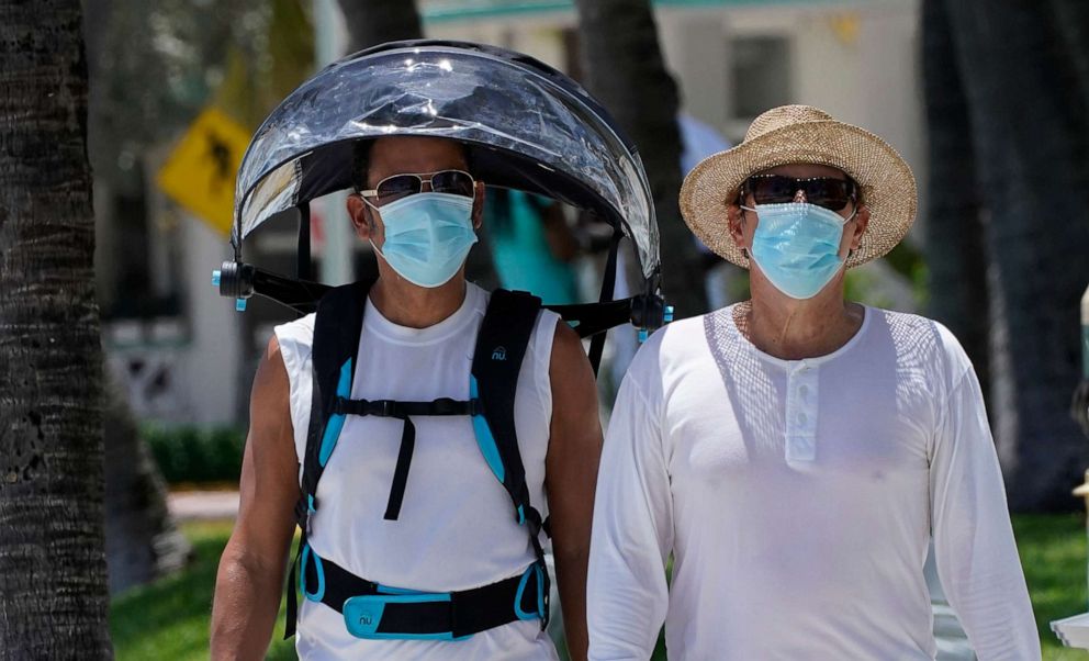 PHOTO: A pair of beach goers wear masks to prevent the spread of COVID-19, Aug. 11, 2020, in Miami Beach, Fla.