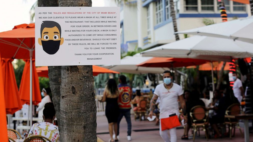 PHOTO: A sign informs customers at the Edison Hotel restaurant about wearing a protective face mask during the coronavirus pandemic, July 24, 2020, along Ocean Drive in Miami Beach, Fla.