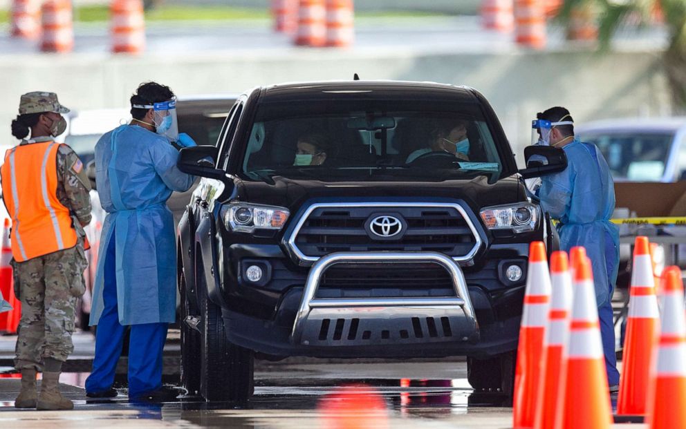 PHOTO: A National Guard troop directs cars as people are tested by healthcare workers at the COVID-19 drive-thru testing center at Hard Rock Stadium, in Miami Gardens, Fla., as the coronavirus pandemic continues, July 19, 2020.