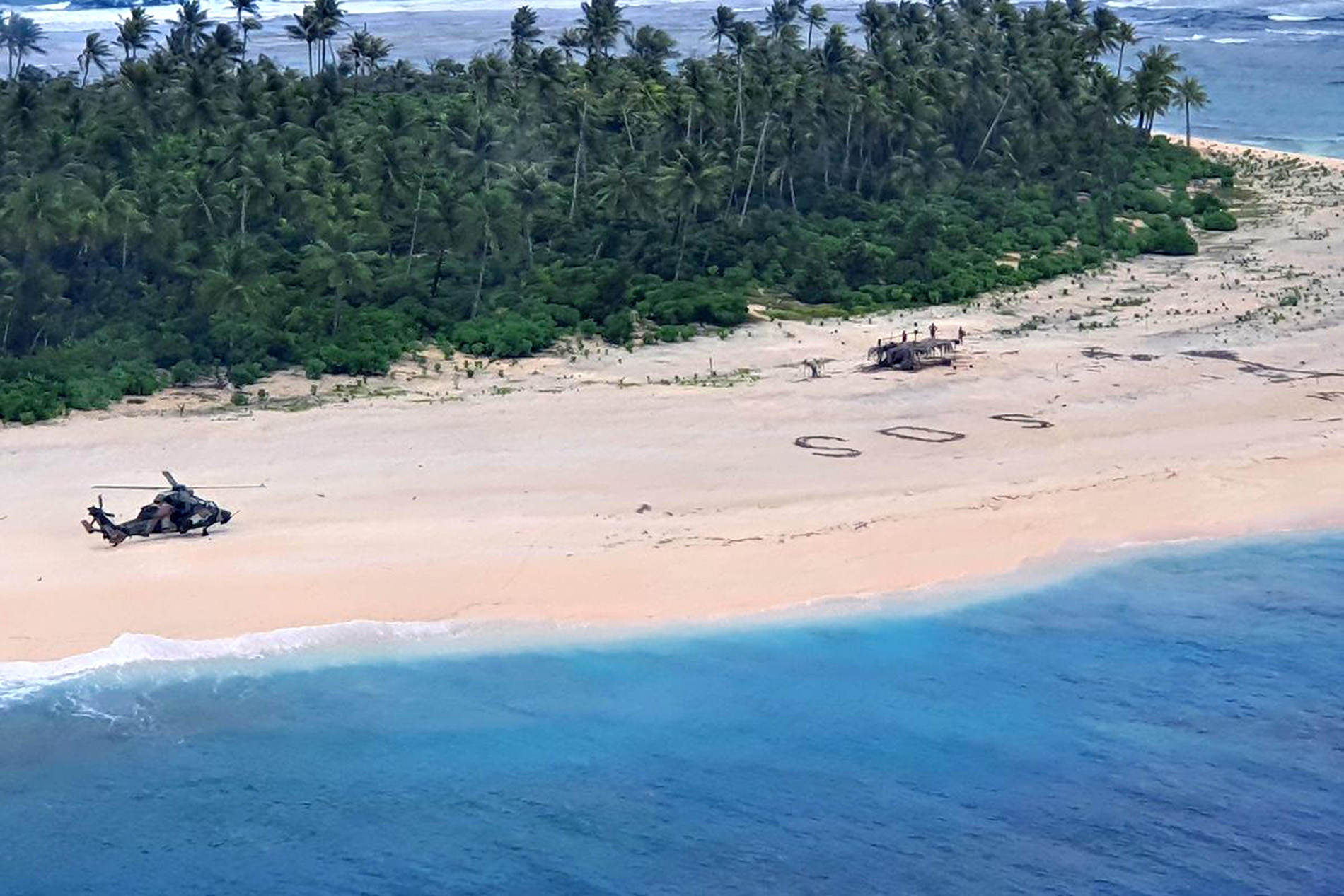 PHOTO: An Australian Army ARH Tiger helicopter lands near the letters "SOS" on a beach on Pikelot Island where three men were found in good condition after being missing for three days, Aug. 2, 2020.