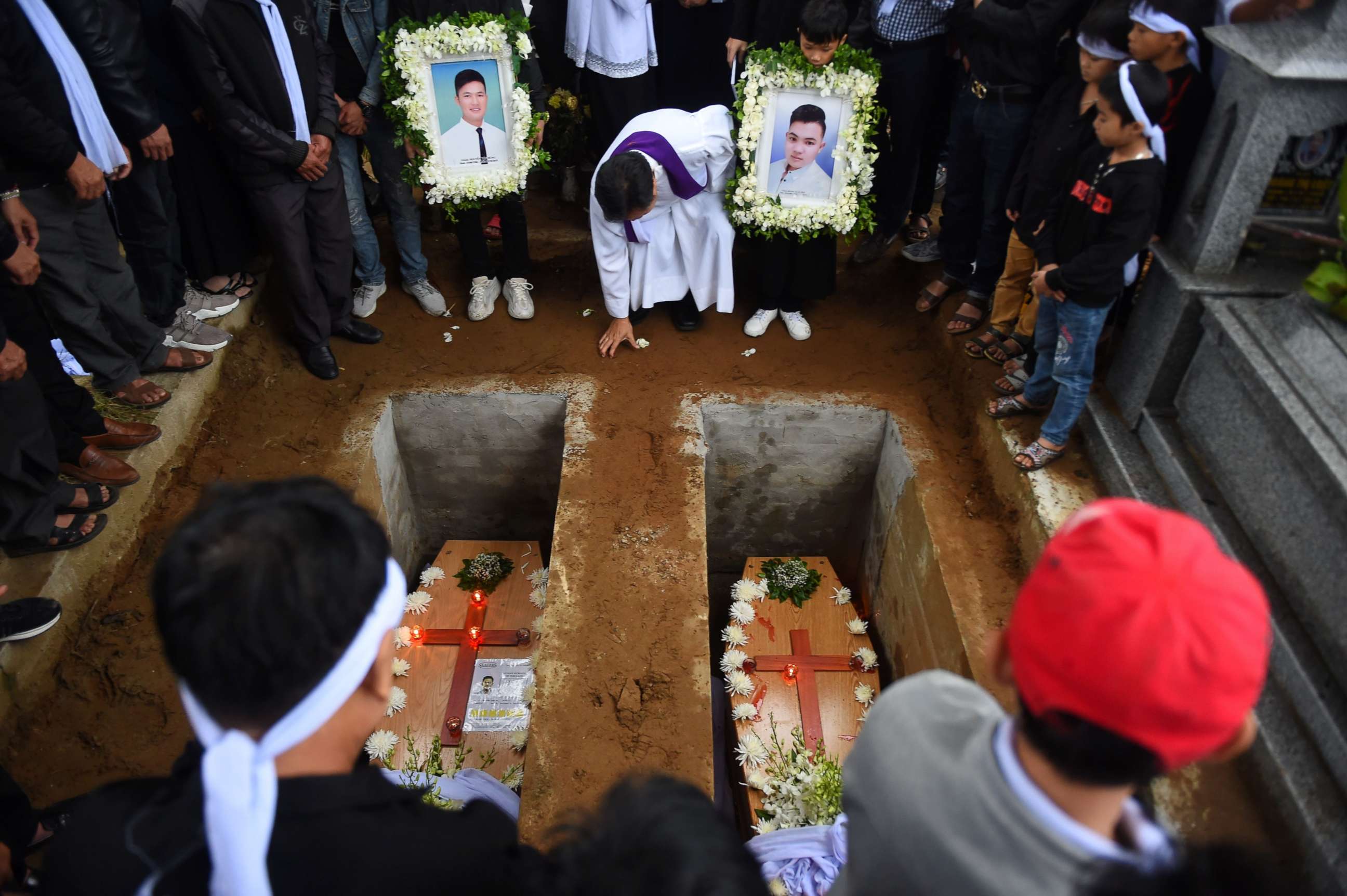 PHOTO: A priest officiates final rites during burial of coffins bearing the remains of two Vietnamese migrants at a cemetery in Dien Chau district, Nghe An province on Nov. 28, 2019.