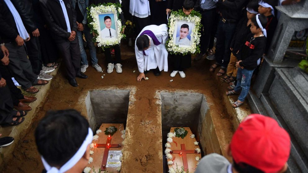 PHOTO: A priest officiates final rites during burial of coffins bearing the remains of two Vietnamese migrants at a cemetery in Dien Chau district, Nghe An province on Nov. 28, 2019.