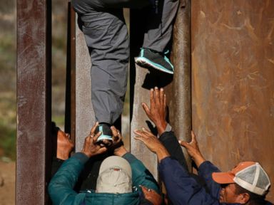 PHOTO: Honduran migrants help each other cross over the U.S. border wall to San Diego, California, from Playas in Tijuana, Mexico, Dec. 12, 2018.