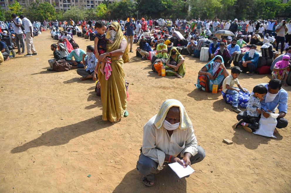 PHOTO: Migrant workers and their families line up inside a park in Mumbai, India, on May 21, 2020, as they await for transportation to a nearby railway station to return by train to their hometowns after the government eased coronavirus restrictions.