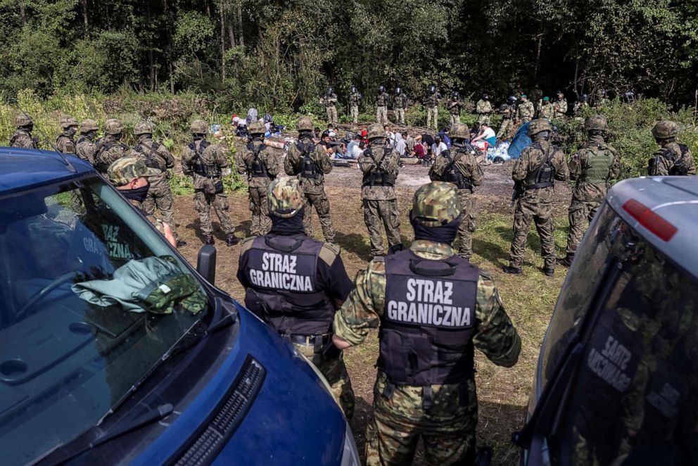 PHOTO: Polish border guards (foreground) stand next to migrants, believed to be from Afghanistan, in the village of Usnarz Gorny, Poland, near the border with Belarus, on Aug. 20, 2021.