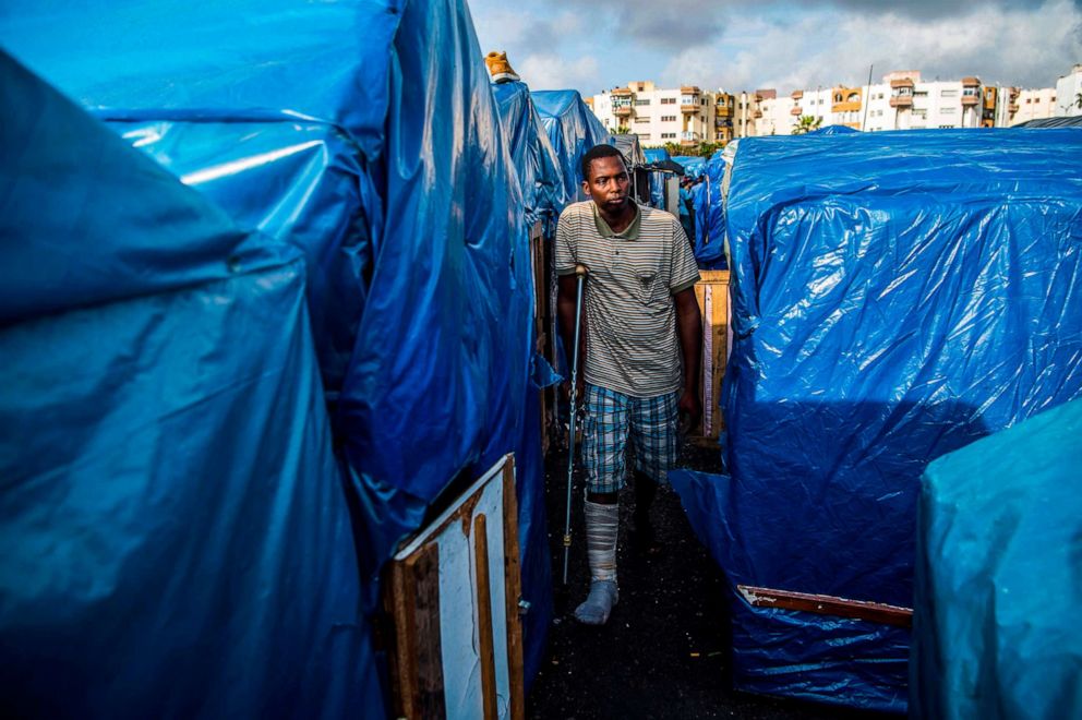 PHOTO: A sub-Saharan migrant with his leg in a cast, walks with a crutch between make-shift tents in the Oulad Ziane migrant camp in Casablanca, Morocco, March 27, 2019.