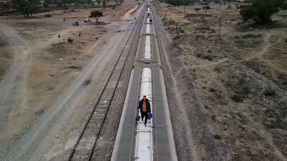 FOTO: Migrantes caminan sobre vagones de ferrocarril mientras se preparan para continuar su viaje hacia la frontera con Estados Unidos en el sitio conocido como El Basurero, un tramo de tierra junto a un basurero y la vía del tren, en Huehuetoca, Estado de México, México , 26 de abril de 2023.