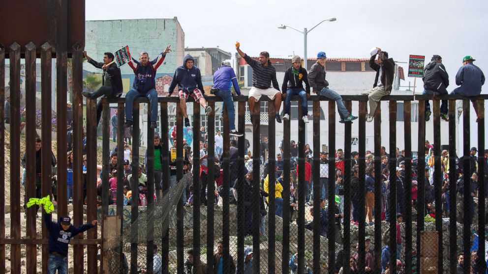 PHOTO: People in Mexico climb the border wall fence as a caravan of migrants and supporters reached the United States-Mexico border near San Diego, Calif., April 29, 2018.