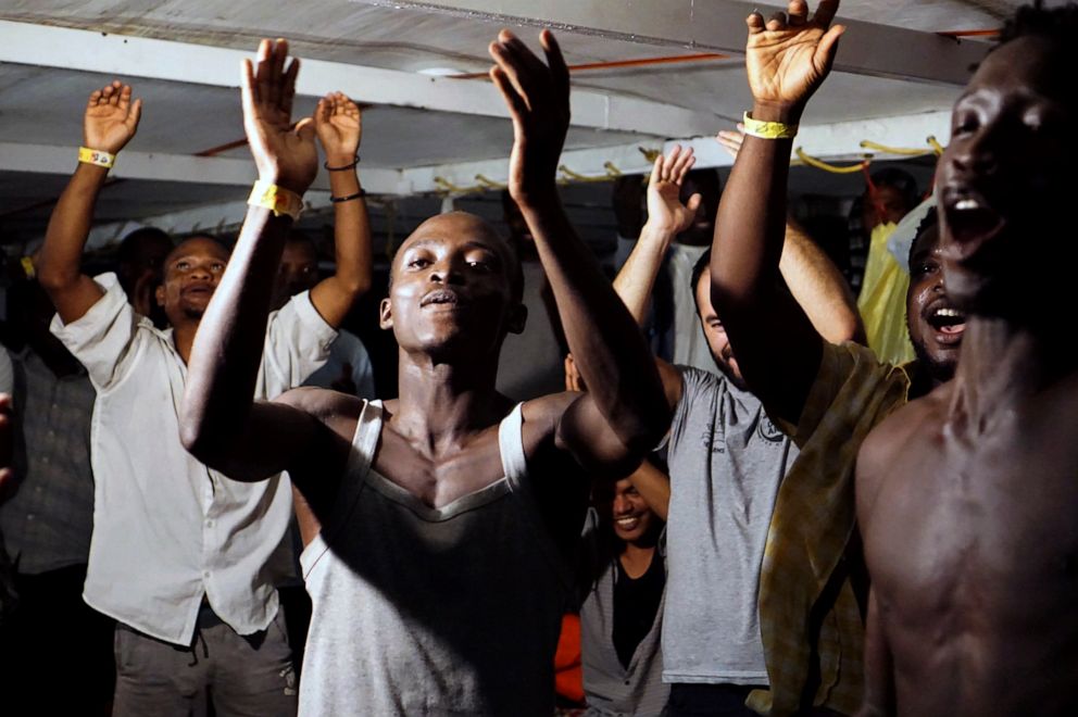 PHOTO: Migrants on board the Open Arms vessel celebrate the news of an Italian prosecutor who has ordered that the migrants be disembarked on the island of Lampedusa, southern Italy, Aug. 20, 2019.