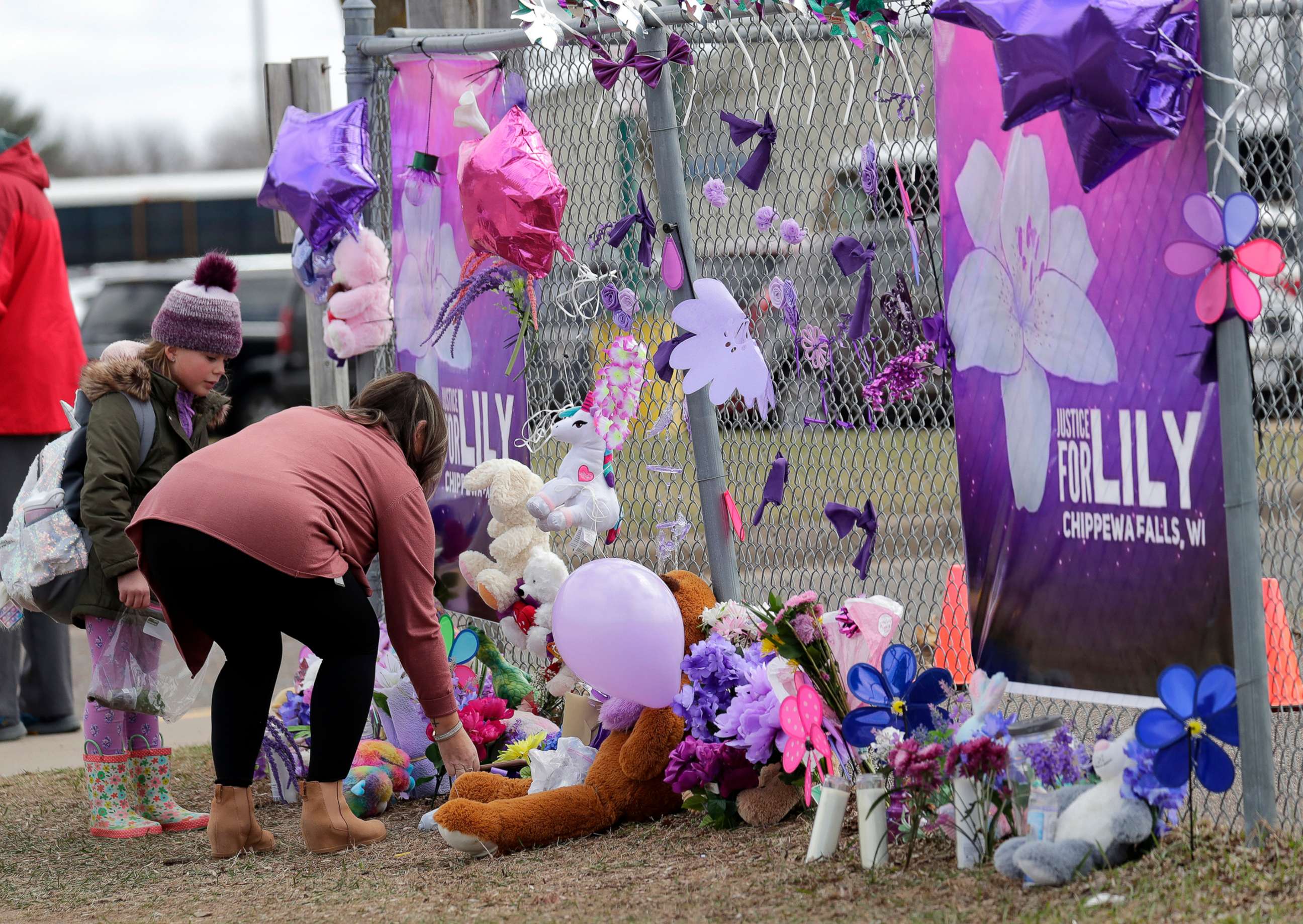 PHOTO: Tiffany Thompson and her step-daughter Lexy Frank, 8, leave a stuffed animal and drawing at a large memorial for Iliana "Lily" Peters at Parkview Elementary School in Chippewa Falls, Wis., April 26, 2022.