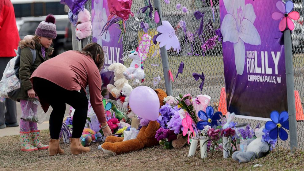 PHOTO: Tiffany Thompson and her step-daughter Lexy Frank, 8, leave a stuffed animal and drawing at a large memorial for Iliana "Lily" Peters at Parkview Elementary School in Chippewa Falls, Wis., April 26, 2022.