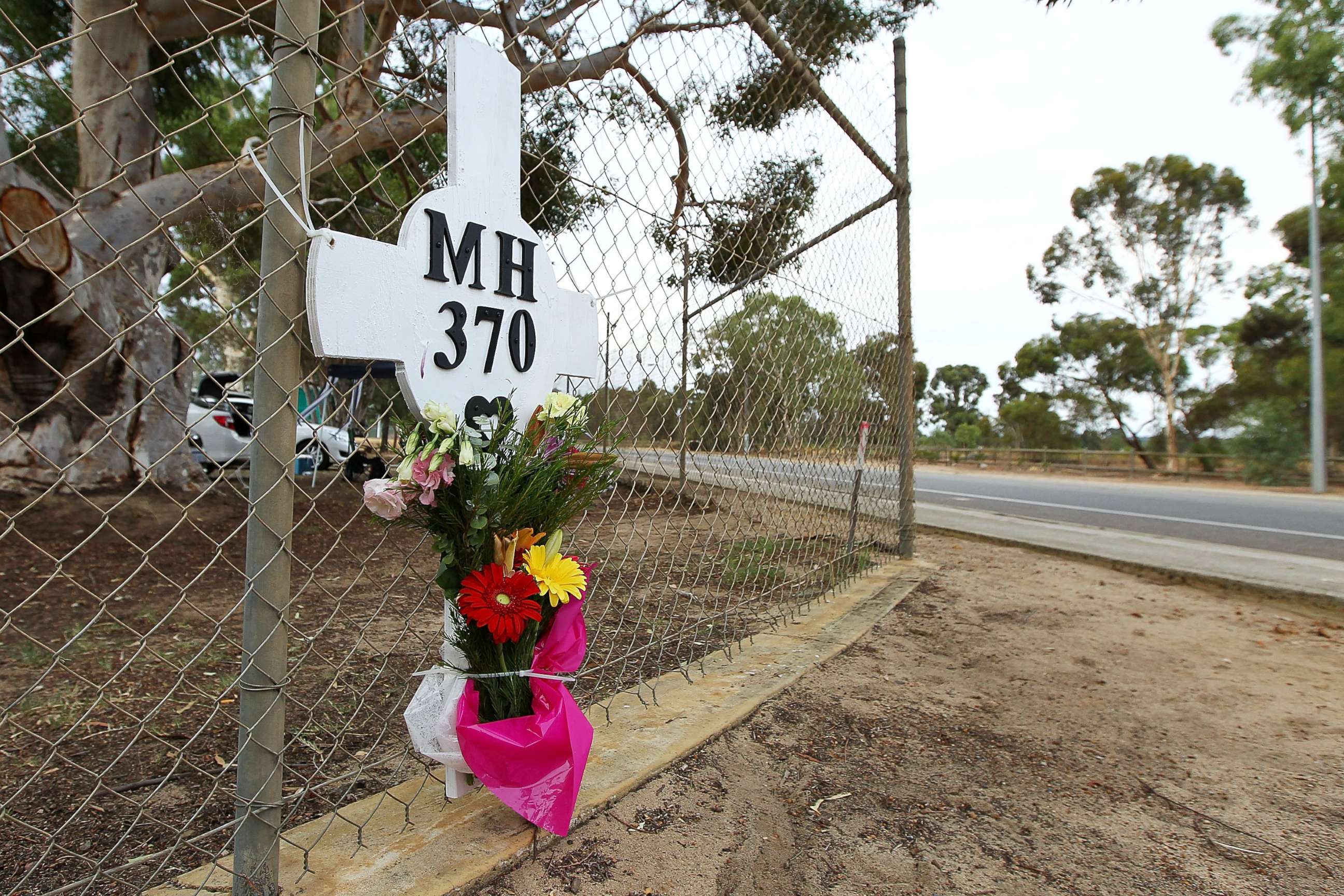 PHOTO: Flowers and a memorial for the missing passengers of flight MH370 are attached to the perimeter fence of RAAF Pearce Airbase on March 26, 2014 in Bullsbrook, 35km north of Perth, Australia.