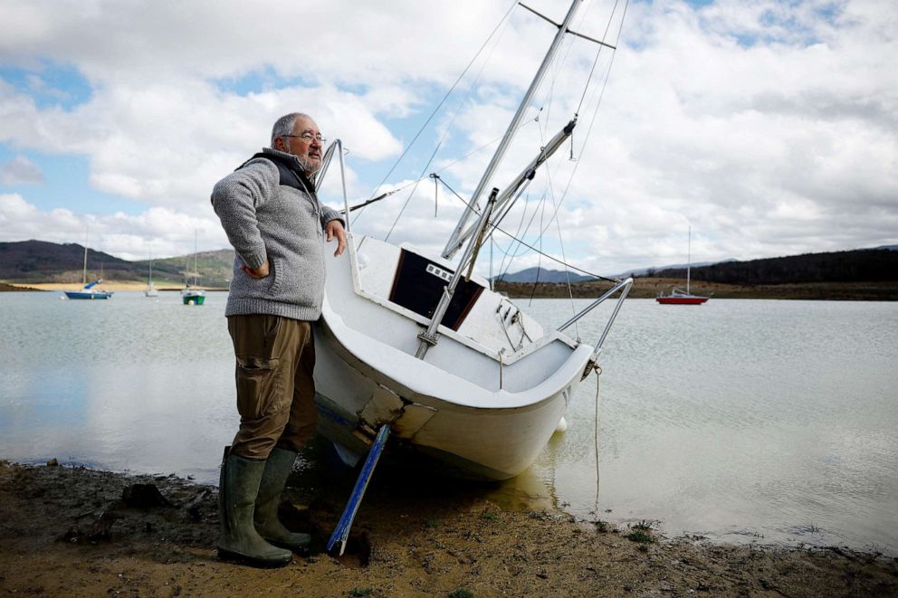 PHOTO: Sailing instructor Claude Carriere stands next to a boat at the partially dry Lake Montbel at the foot of the Pyrenees Mountains as France faces the potential of another summer of droughts and water restrictions, March 15, 2023.