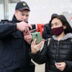 A police officer checks a digital code shown by a commuter during an ID check at Planernaya Station of the Moscow Underground during the novel coronavirus pandemic, April 13, 2020, in a photo released by the Russian state.