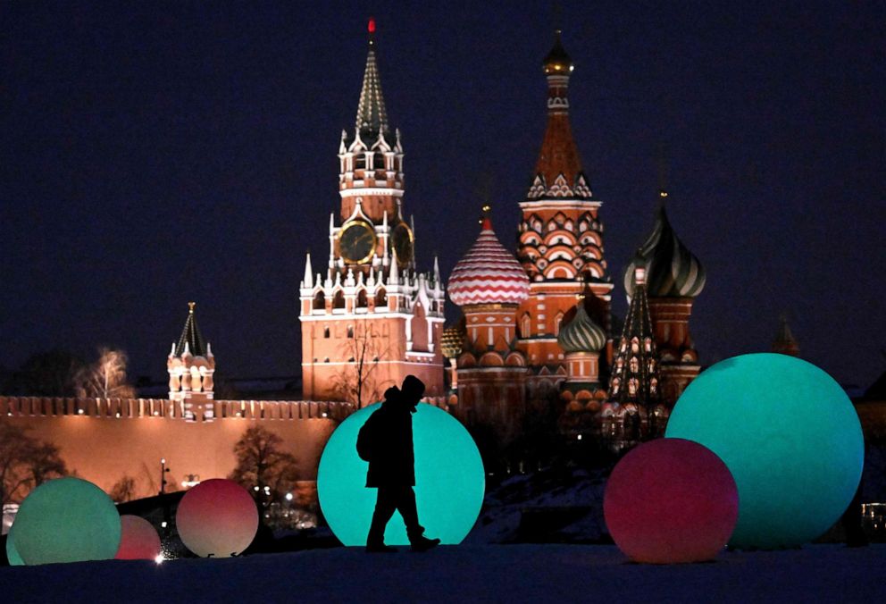 PHOTO: People walk past light installations at Zaryadie park in front of the Spasskaya tower of the Kremlin and the Saint Basil cathedral, in Moscow on Feb. 19, 2023.
