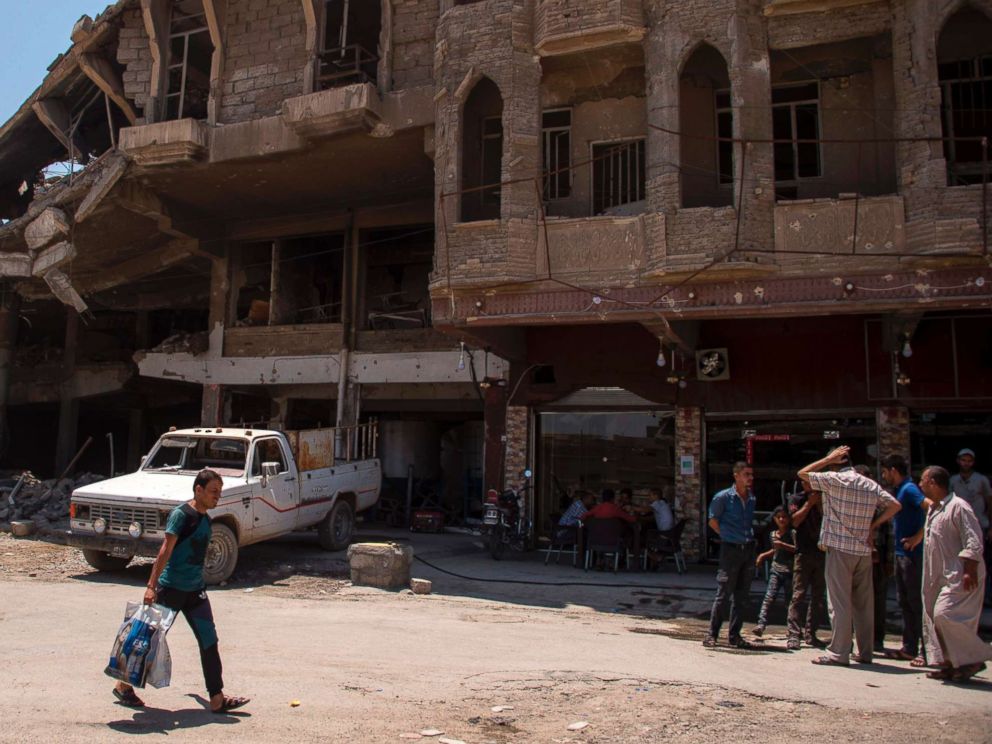 PHOTO: Iraqis gather outside a shop in west Mosul, July 12, 2017, a few days after the governments announcement of the liberation of the embattled city from Islamic State (IS) group fighters.