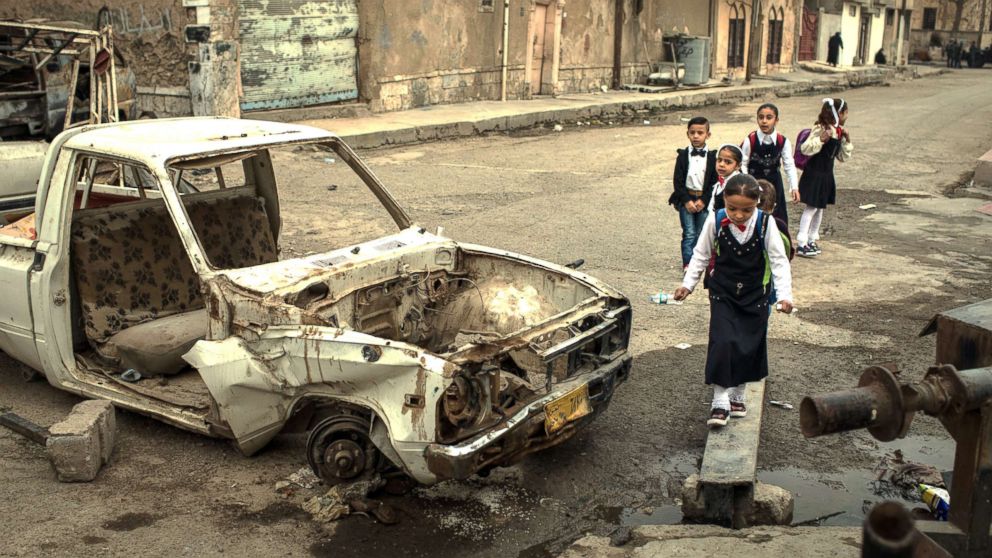 PHOTO: Children walk to school past destroyed cars in West Mosul on Nov. 6, 2017.