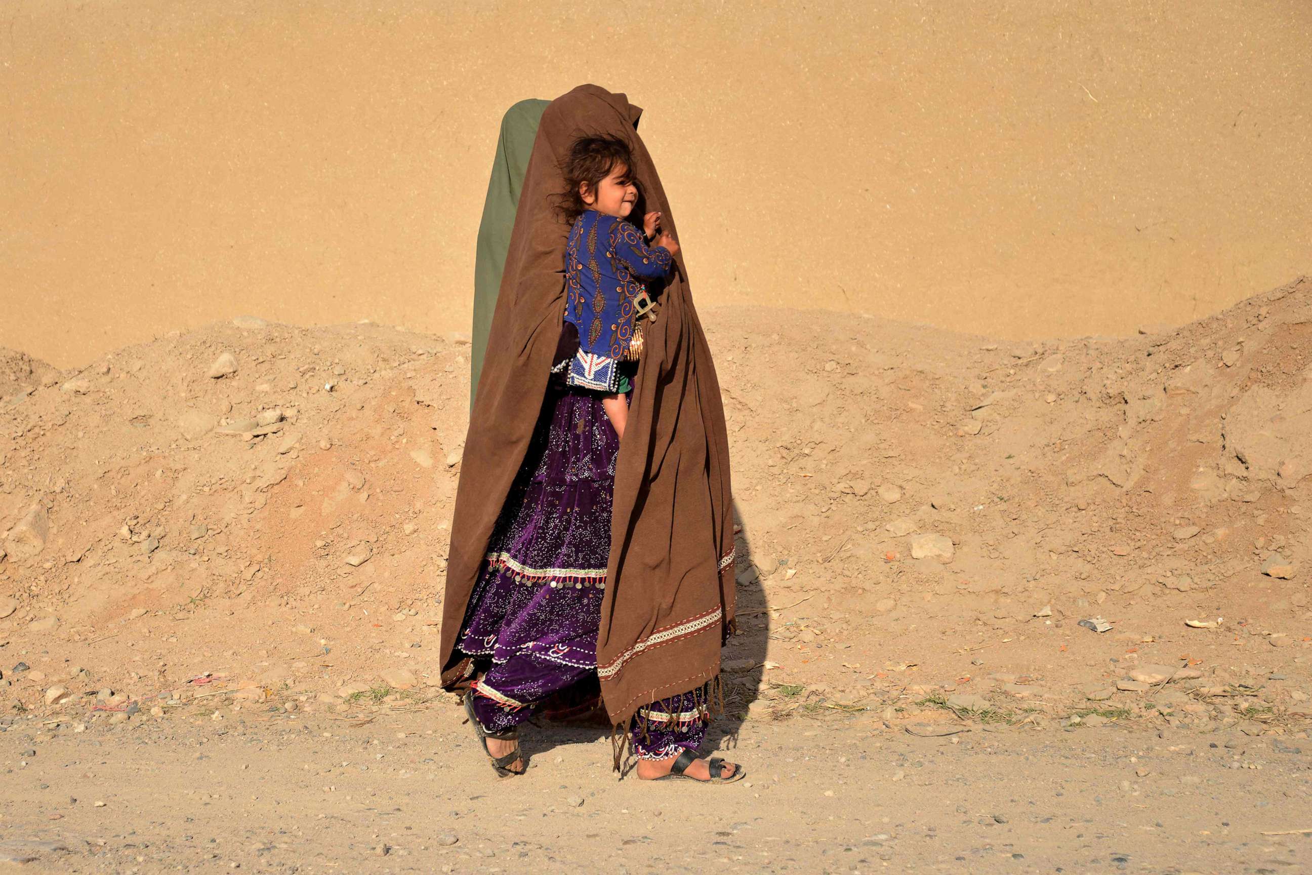 PHOTO: TA woman carrying a child walks along a roadside in the Zhari district of Kandahar province, Afghanistan, on Feb. 15, 2023.