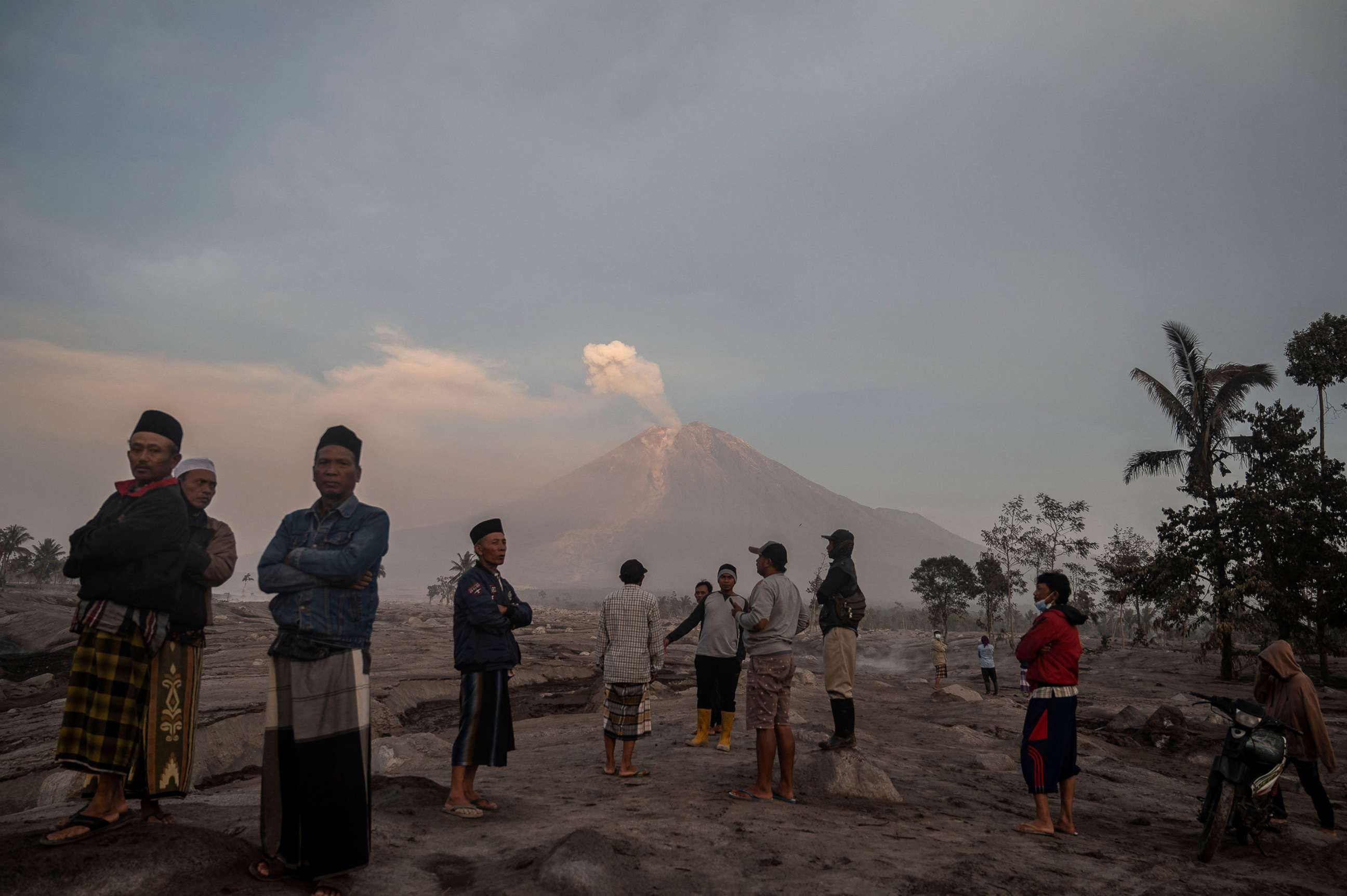 PHOTO: People stand before Mount Semeru following a volcanic eruption at Kajar Kuning village, Dec. 5, 2022, in Lumajang Regency, Indonesia. 